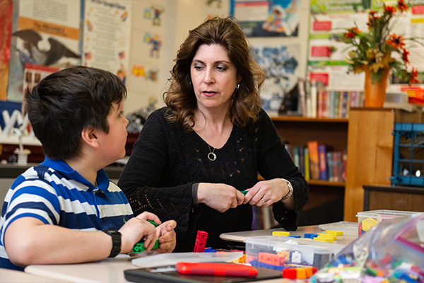 A teacher teaching a student with blocks